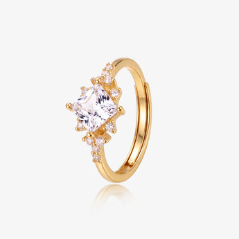 Anillo abierto dorado con circonita cúbica cuadrada y piedras laterales sobre fondo blanco