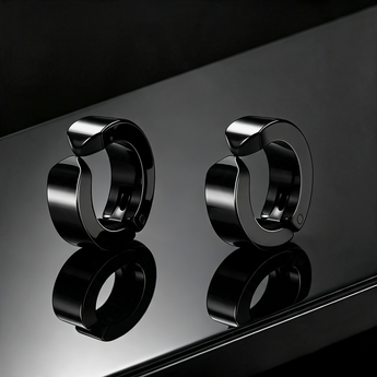pair of black clip-on hoop earrings on a glossy black surface
