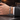 Cuban chain bracelet with engraved clasp worn on wrist beside a suit sleeve