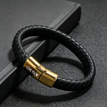 Pulsera trenzada negra con cierre tono dorado grabado con LOVE YOU sobre una superficie oscura