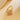 Gold-tone four-leaf clover ring with clear stones on a warm beige satin background