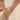 Woman wearing gold-tone layered bead chain bracelet with hand in pocket