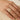 hand wearing a gold-tone open wrap ring with white marbled inlay, close-up