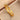 Pulsera rígida dorada con detalles redondos sobre tela beige junto a una caja