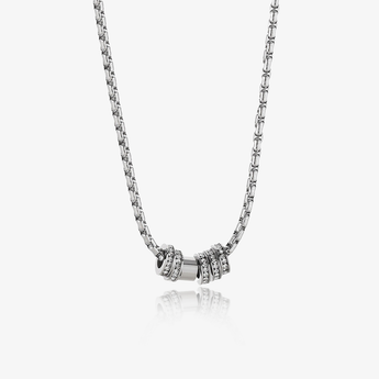 silver-tone chain necklace with three stacked ring pendants, two set with clear stones, on a light background