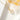 Gold-tone four-leaf clover necklace on white marble beside amber-toned glass