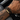 Hombre con una pulsera de cuero trenzado negro y placa dorada grabada en la muñeca