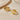 Pair of gold-tone twisted triple hoop earrings on a cream satin surface