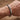 Primer plano de la pulsera de cadena de acero de titanio color plata en la muñeca, fondo de madera